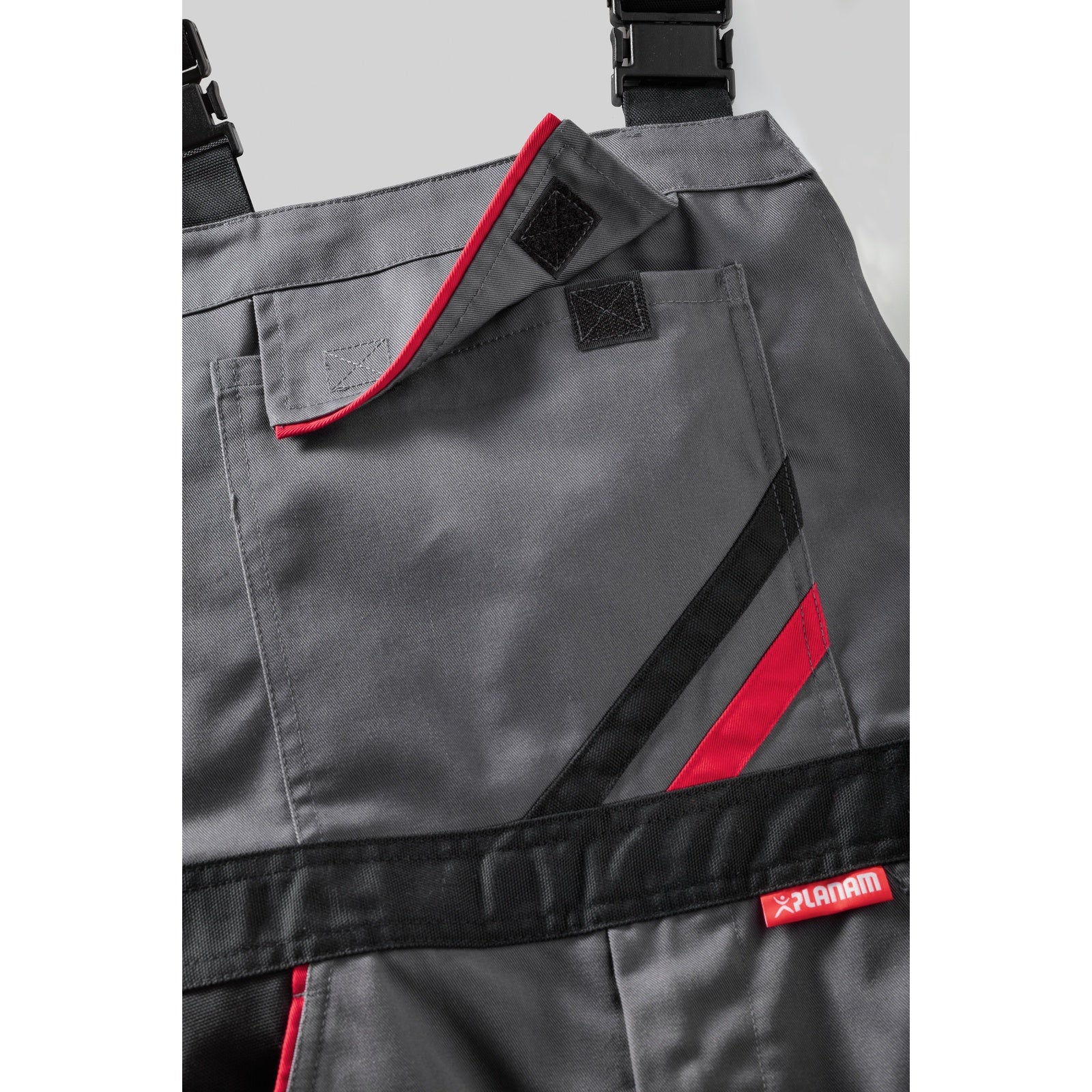Planam Highline Dungarees green/black/red - The bib pocket with flap and Velcro closure provides optimal storage space.